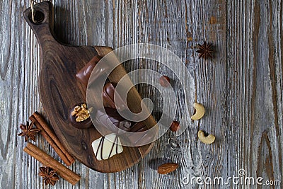 Chocolates in different shapes and colors over rustic wooden board. Stock Photo