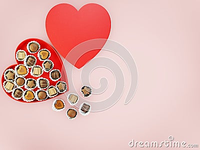 Chocolates sweets in a red heart shaped box with copyspace for text over a pink flatlay background Stock Photo