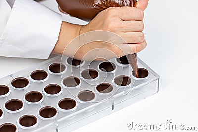 Chocolatier pouring praline filling into chocolate mold preparing belgium candy Stock Photo