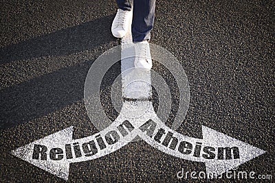 Choice between atheism and religion. Man walking towards drawn marks on road, closeup. Arrows with words pointing in opposite Stock Photo
