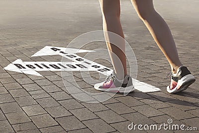 Choice between atheism and religion. Woman walking towards drawn marks on road, closeup. Arrows with words pointing in opposite Stock Photo