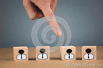 Choice of an employee leader from the crowd. the hand points to the wooden cube that symbolizes that the hand makes the choice Stock Photo