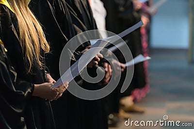 Choir singers holding musical score and singing on student graduation day in university, college diploma commencement Stock Photo