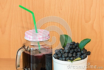 Chokeberry or Aronia melanocarpa juice with ice in glass with straw and berry in basket Stock Photo