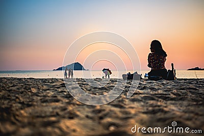 CHONBURI / THAILAND - January 04 2020 : Silhouette Young woman is sitting on sand with the sunset background Editorial Stock Photo