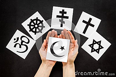 Choose religion concept. Hand with Islam crecent near world religions symbols on black background top view Stock Photo