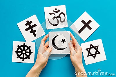 Choose religion concept. Hand with Islam crecent near world religions symbols on blue background top view Stock Photo