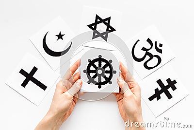 Choose religion concept. Hands with Buddhist wheel near world religions symbols on white background top view Stock Photo