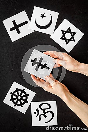 Choose religion concept. Hands with Orthodox cross near world religions symbols on black background top view Stock Photo