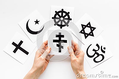 Choose religion concept. Hands with Orthodox cross near world religions symbols on white background top view Stock Photo