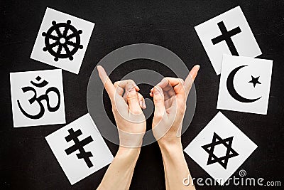 Choose religions concept. Hands point on Christianity, Catholicism, Buddhism, Judaism, Islam symbols on black background Stock Photo