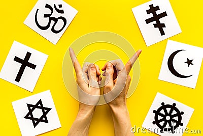 Choose religions concept. Hands point on Christianity, Catholicism, Buddhism, Judaism, Islam symbols on yellow Stock Photo