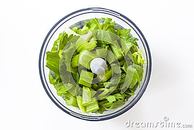 Chopped fresh celery in a blender on white background. Top view. Close up image Stock Photo