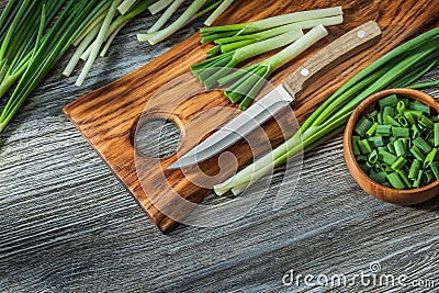 Chopped green spring scallions kitchen knife wooden cutting board vintage wood background Stock Photo