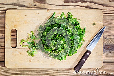 Chopped spinach, lettuce, parsley on cutting Board with knife. Stock Photo