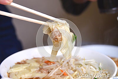 Chopsticks holding wonton noodle. Stock Photo