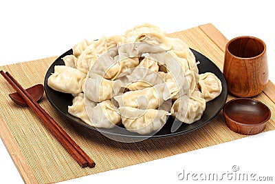 Chopsticks Pick Up Boilded Chineses Dumplings from a Plate. The Dumpling, called Jiaozi in Chinese, is a popular traditional Chine Stock Photo