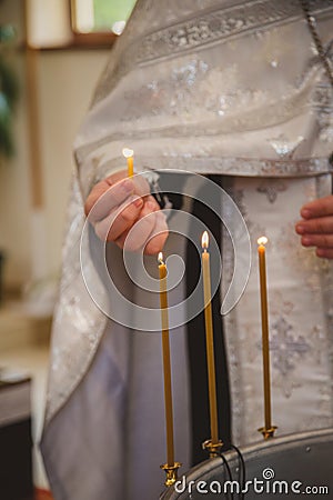 Christening in the church, priest is lighting candles at children baptismal font. Details in the orthodox christian church Editorial Stock Photo