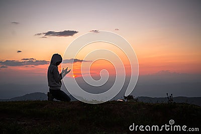 A Christian girl prays to God on top of mountain and sunset. Religious beliefs, Copy space Stock Photo