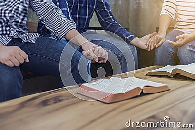 A christian group holding hands and together over blurred bible on wooden table, fellowship or bible study concept Stock Photo