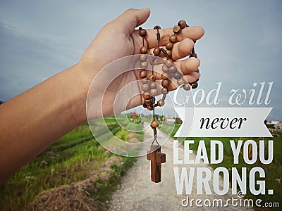 Christian inspirational quote - God will never lead you wrong. With junior hand holding wooden rosary with Jesus Christ cross Stock Photo