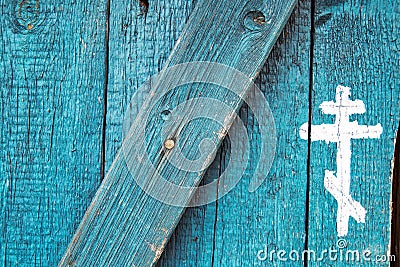 Christian Orthodox cross drawn of white paint on old blue wooden door. Silhouettes of crucifix symbol. Christianity Stock Photo