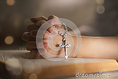 Christian woman hand on holy bible worship to god holding cross rosary Stock Photo