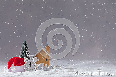 Christmas alarm clock, Santa Claus` hat, small wooden toy cottage and fir-tree with balls, postcard concept Stock Photo