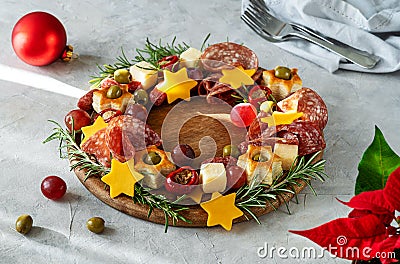 Christmas appetizers wreath on wooden board and grey background, star of Christmas plant or Poinsettia, napkin, forks Stock Photo