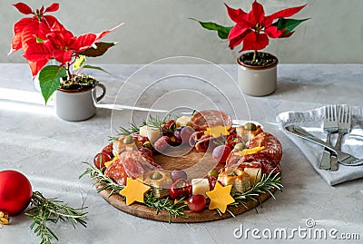 Christmas appetizers wreath on wooden board and grey background, star of Christmas plant or Poinsettia, napkin, forks Stock Photo