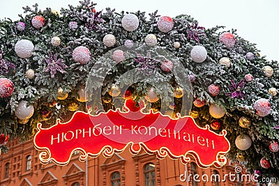 Christmas arch decorated with baubles and snow. Red signboard with word in Russian Nuremberg - Copenhagen . Moscow Seasons Project Editorial Stock Photo