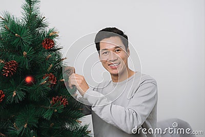 Christmas. Asian man standing new christmas tree at home celebrating New Year. Stock Photo