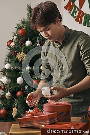 Christmas. Asian man standing new christmas tree at home celebrating New Year. Stock Photo