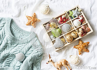 Christmas background. Box of vintage christmas decorations and blue knitted sweater on the bed, view from above. Christmas cozy mo Stock Photo