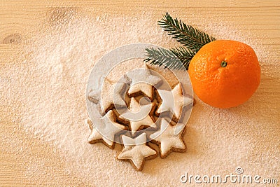 Christmas background with cinnamon stars and a tangerine and a pine branch on wood Stock Photo