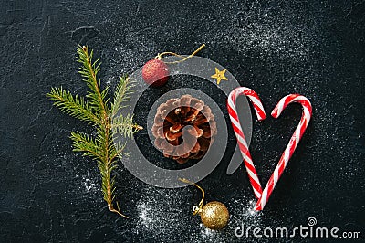 Christmas background. Fir tree branch, cone, candy canes, balls, on a black snowy background. Stock Photo