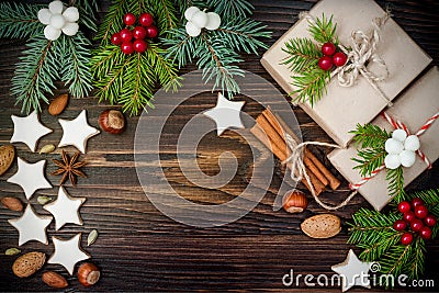 Christmas background with gingerbread cookies, fir branches and presents in boxes on the old wooden board. Copy space. Stock Photo