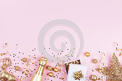 Christmas background with golden gift or present box, champagne and holiday decorations on pink pastel table top view. Flat lay. Stock Photo