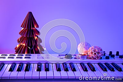 Christmas background with midi keyboard and holiday decor with neon lights. Stock Photo