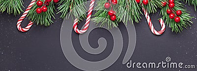 Christmas background with tree branches, candy cane and holly on black wooden background. Snowfall drawing effect Stock Photo