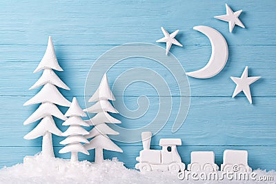 Christmas background with white Christmas trees, toy train, snow, moon and stars, blue wooden background Stock Photo