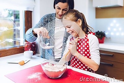 Christmas bakery. Mother and daughter making gingerbread, preparing eggs, flour and honey for gingerbread dough. Stock Photo