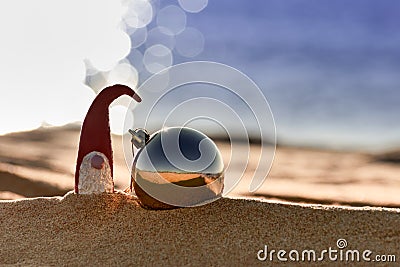 Christmas ball and Santa Claus or dwarf on beach against background of sea. New Year and Christmas celebration concept Stock Photo