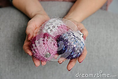 Christmas balls made of knitted threads in the hands of a girl, knitted Christmas toys Stock Photo