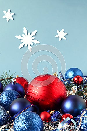 Christmas balls-red and blue-with festive tinsel on a blue background with snowflakes, side view, vertical frame Stock Photo