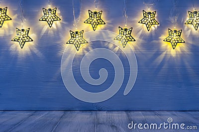 Christmas blank interior with glow lights yellow stars on indigo blue wood background. Stock Photo