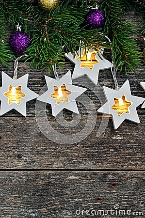 Christmas Border: cozy warm lights garland stars and fir branches on rustic wooden background. top view. over hand Stock Photo