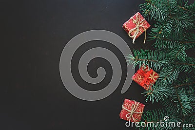 Christmas Border. Fir tree branches with gift boxes on dark wooden background. Top view. Copy space. Stock Photo