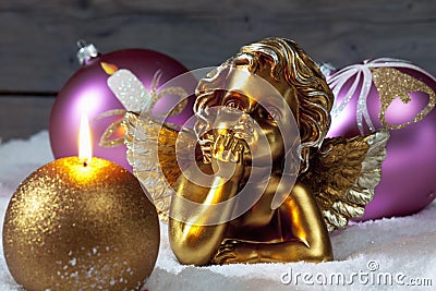 Christmas bulbs burning candle golden putto on pile of snow Stock Photo