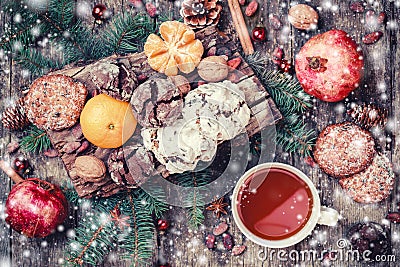 Christmas card. Christmas Cookies Chocolate, tea, pomegranate, Tangerines, Nuts, cocoa beans, Fir branches on wooden snowy backgro Stock Photo